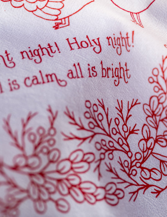 Illustration detail of Our Silent Night Christmas hymn tea towel, which features a hand-illustrated floral border and hand-lettered text, printed in holly berry red on a 100% cotton tea towel.