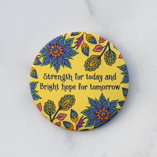 The "Strength For Today" hymn button features lines from the beloved hymn "Great Is Thy Faithfulness" The text is surrounded by a vibrant floral design with a butter yellow background. Shown here against a gray marble background.