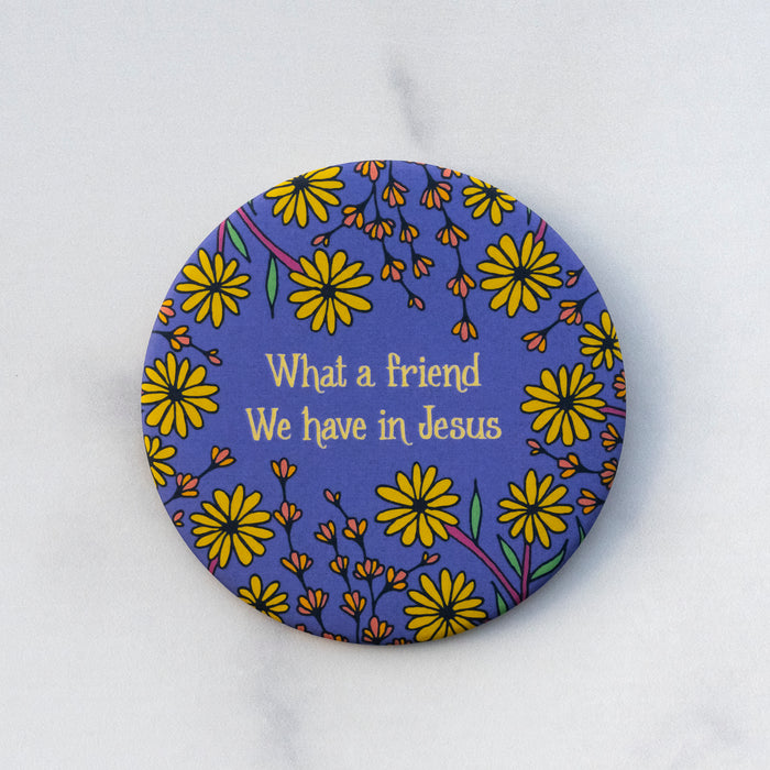 The "What a Friend" hymn button features lines from the beloved hymn "What a Friend We Have in Jesus" surrounded by friendly florals with a blueberry purple background; shown here against a gray marble background.