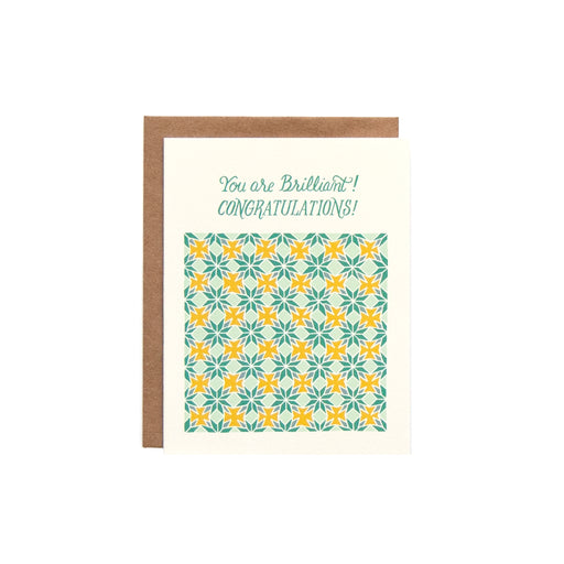 The Congratulations greeting card features a hand illustrated patterned floral highlighted with blues and yellows on a cream background with a blank inside, shown against a white backdrop.