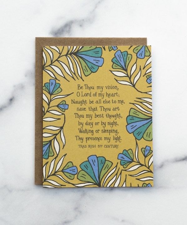The Be Thou My Vision hymn greeting card, framed by rainforest green and stormy blue colored florals against a saffron background, shown with a kraft paper envelope against a marble background.