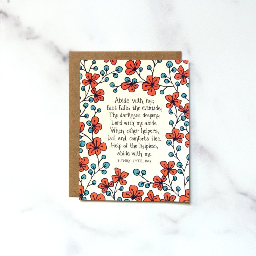 "Abide With Me" Greeting Card features hand lettered hymn text framed by a vibrant red and blue floral, shown against a marble backdrop.