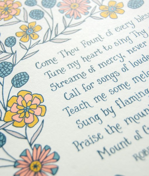 Hand lettered text detail of Come Thou Fount hymn art print — faith based wall decor on a white background accented by illustrated floral design in yellow, orange, teal, and green