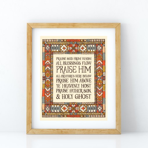 Doxology wall art featuring hand lettered text surrounded by a multi-coloured stained glass illustration, displayed in a light wood frame