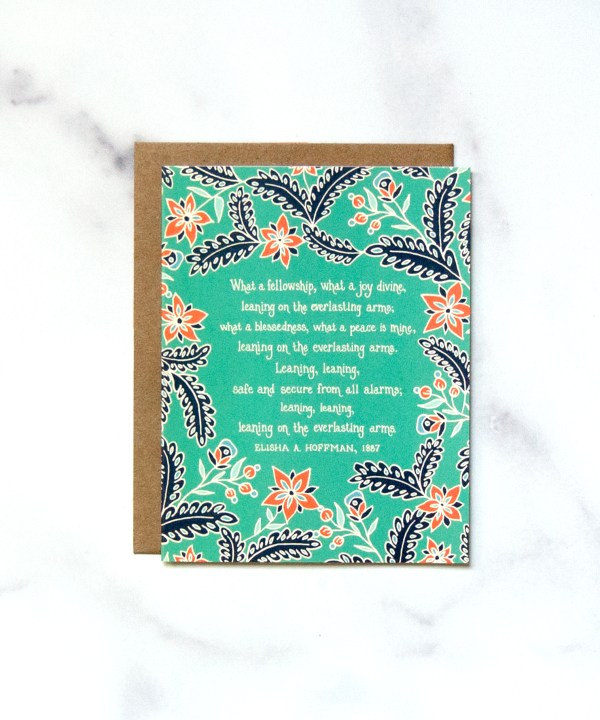 Little Things Studio's "Leaning on the Everlasting Arms" Greeting Card features the beloved hymn text, framed by a lively coral and navy floral with a serene green background, shown against a marble backdrop.