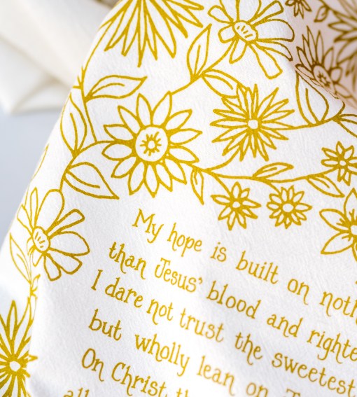 Our "My Hope Is Built" hymn tea towel features whimsical floral illustration and hand lettered hymn text printed in fresh Sicilian green, seen clearly in this close-up image of the towel.