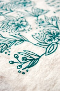 Floral detail of This is My Father's World tea towel, printed in emerald green and features hand lettered hymn text surrounded by intricate floral illustration