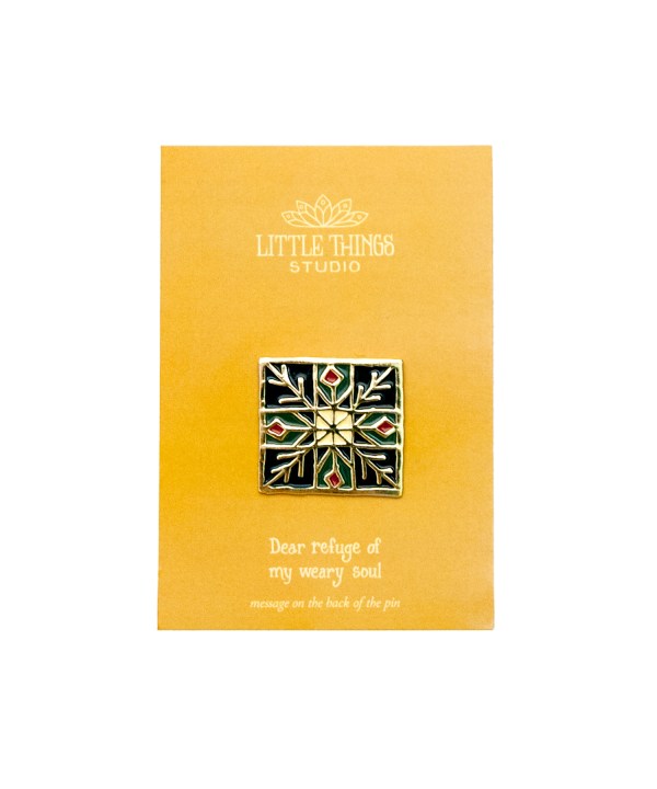The Dear Refuge enamel pin, shown with its goldenrod cardboard backer.