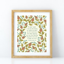 We Gather Together hymn wall art featuring hand lettered text on a cream background surrounded by illustrated floral design in red-orange, teal, and olive green displayed in a light wood frame