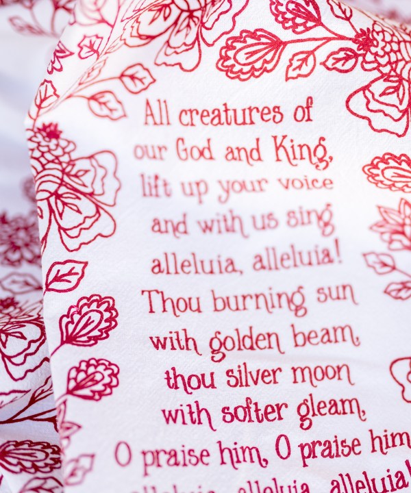 Floral and text detail of All Creatures of our God and King tea towel is printed in rich crimson