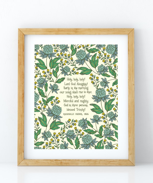 Holy Holy Holy art print — biblical wall art featuring hand lettered text surrounded by floral illustrations in shades of blue, yellow, and green, displayed in a light wood frame.
