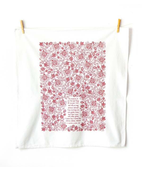 All Creatures of our God and King Scripture tea towel is printed in rich crimson, displayed folded against a white marble background