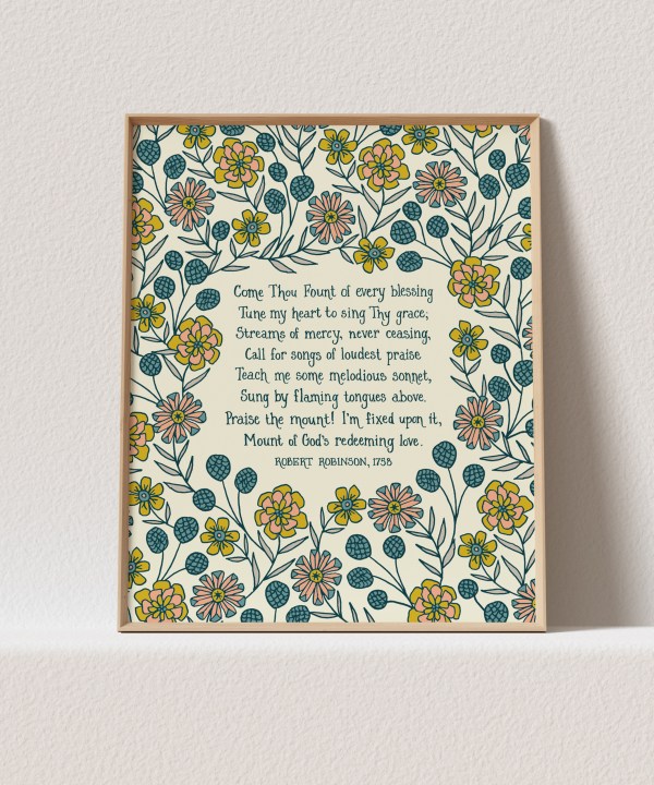 This "Come Thou Fount" hymn art print features the beloved hymn text surrounded by a lively floral and will brighten up any room. Shown in a light wood frame against a white background.