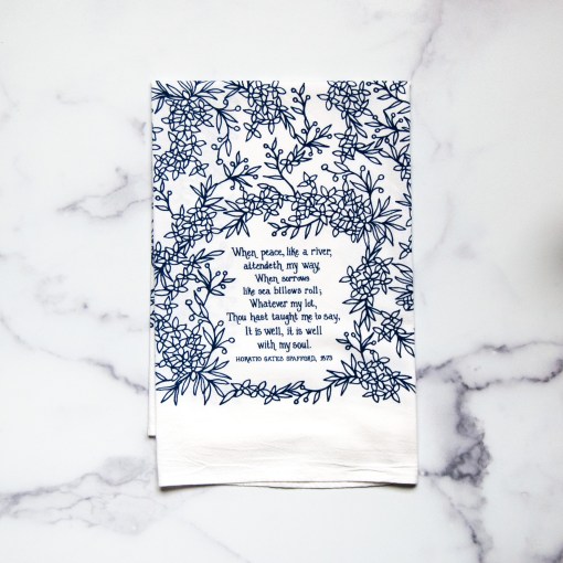 It Is Well With My Soul tea towel is printed in a striking cobalt blue and is shown folded and lying against a white marble background.