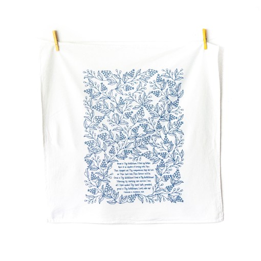 Great Is Thy Faithfulness tea towel — one of our Christian dish towels — is printed in a striking cerulean blue. The hand lettered text is surrounded by illustrated floral design, and the towel is shown unfolded and hanging with clothes pins.