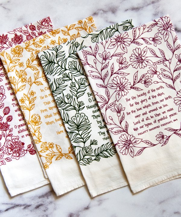 4 Bible verse tea towels, set #2, featuring four beloved hymns all printed in vibrant colors on cotton tea towels, shown folded and lying against a white marble background.