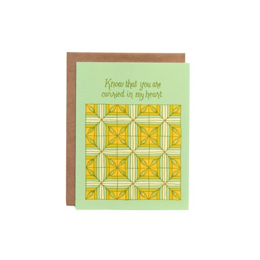 Carried in My Heart Greeting Card features he hand illustrated patchwork pattern highlighted in greens and yellows, pictured against a white background.