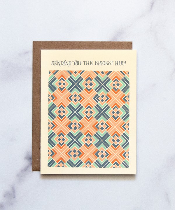 The Biggest Hug Greeting Card features a hand illustrated geometric pattern in blues and corals— a beautiful greeting card pictured against a white marble background.