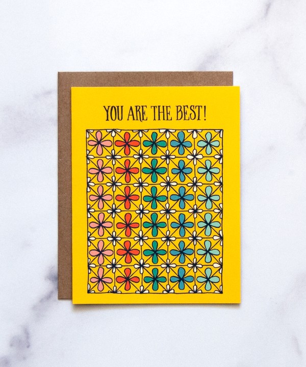 The "You Are the Best!" Greeting Card features hand illustrated patterned floral in an array of rainbow colors on a bright yellow background, shown here against a marble backdrop.