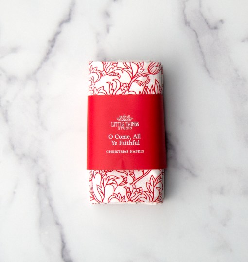 "O Come All Ye Faithful" cloth napkins use the same flour sack cotton as our tea towels and are printed in a vibrant Christmas red with a beautiful floral illustration and the text printed around the edge. Shown here folded with a paper belly band for gift giving.