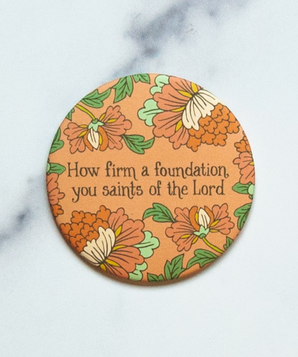 "How Firm A Foundation"hymn magnet design features bold floral over a salmon pink background. Shown against a marble backdrop.