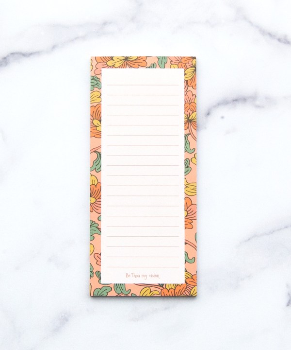 The "Be Thou My Vision" notepad features a hand illustrated floral border, "Be Thou my vision" at the bottom, and a magnet on back, shown against a white marble background.