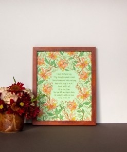Jesus Paid It All art print — a religious wall hanging featuring hand-lettered hymn text printed on a light green background surrounded by floral accents in pink, light red, white, orange and green, displayed in a dark wooden frame with a vase of fresh flowers
