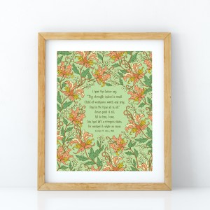 Jesus Paid It All art print — hand-lettered hymn text printed on a light green background surrounded by floral accents in pink, light red, white, orange and green, displayed in a light wood frame.