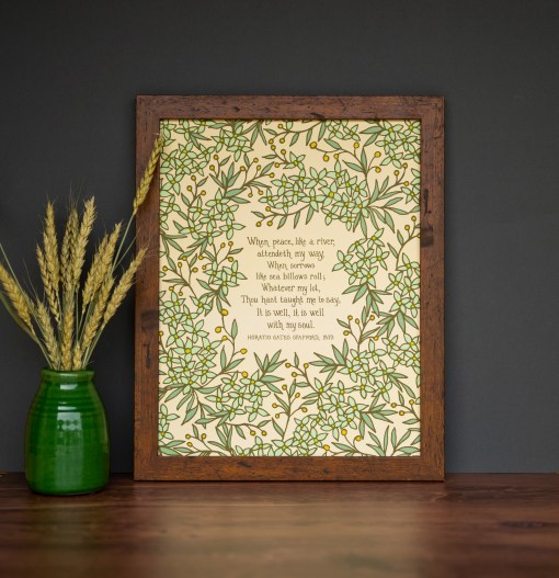 It is Well 11x14 Hymn Wall Art featuring light green floral surrounding the handwritten hymn on a cream background styled in a dark wood frame with a green vase and dried grasses