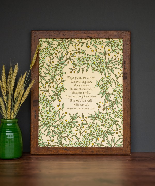 It is Well 11x14 Hymn Wall Art featuring light green floral surrounding the handwritten hymn on a cream background styled in a dark wood frame with a green vase and dried grasses.