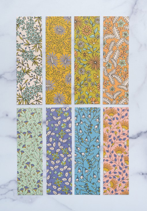 Set of 8-Hastings hymn bookmarks feature whimsical floral illustration and hand lettered hymn text, displayed face down in two rows, shown against a white marble backdrop.