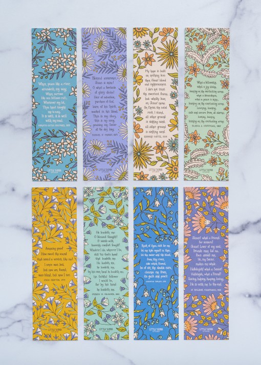 Set of 8-Hastings hymn bookmarks featuring vibrant colors and classic hymns, face up in two rows, shown against a white marble backdrop.