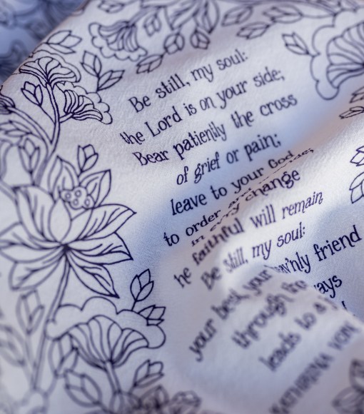 Text and illustration detail of The Be Still, My Soul tea towel featuring the beloved hymn is printed in a deep eggplant purple.