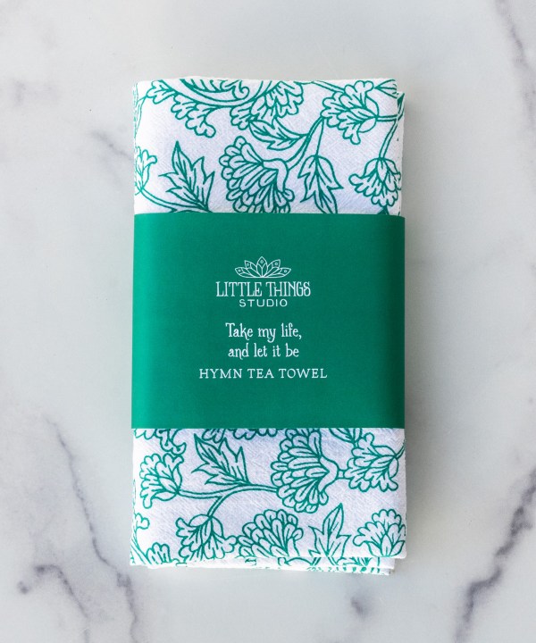 The Take My Life and Let It Be hymn tea towel featuring the beloved hymn is printed in an aqua green, shown folded with a paper belly band for gift giving.