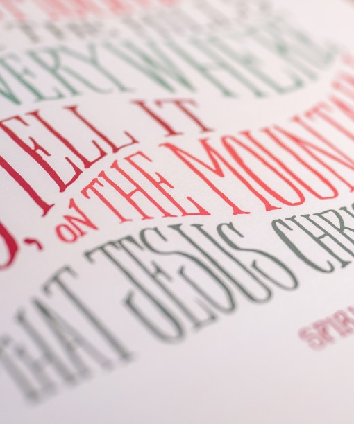 Hand lettered text detail of Go Tell It on the Mountain Christmas hymn art print features festive multi-colored, hand-lettered text against a cream background