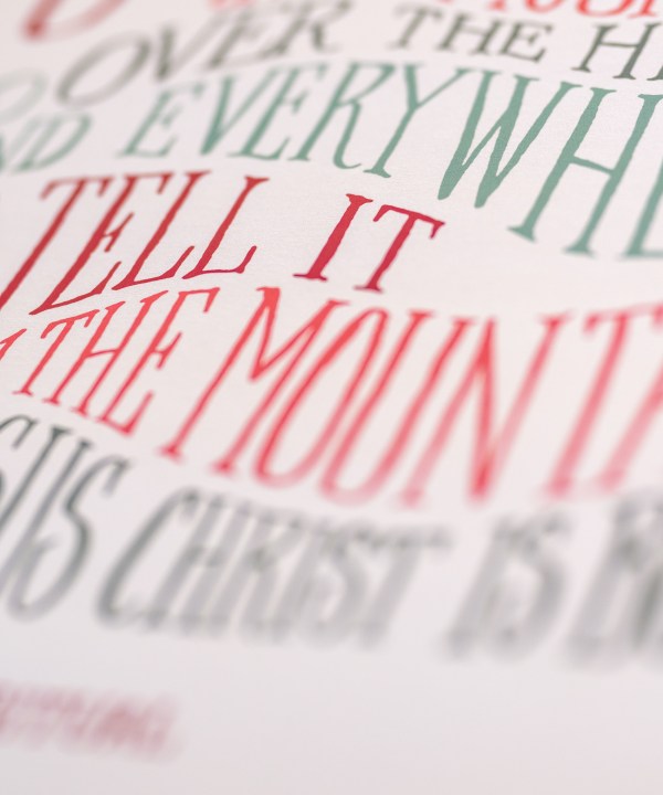 Hand lettered text detail of Go Tell It on the Mountain Christmas hymn art print features festive multi-colored, hand-lettered text against a cream background