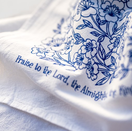 Detail image of "Praise to the Lord" hymn cloth napkins use the same flour sack cotton as our tea towels. These are printed in blueberry with a beautiful floral illustration and the hymn text printed around the edge.