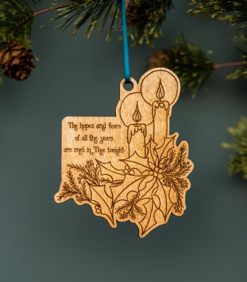 All-new Christmas ornaments from Little Things Studio include these exquisite candlelight ornaments, featuring intricately-etched design bursting with holly and winter greenery and engraved with lyrics from the Christmas carol “O Little Town of Bethlehem.” Laser cut in-house from bright maple plywood grown in North Carolina. Shown hanging from a Christmas tree.