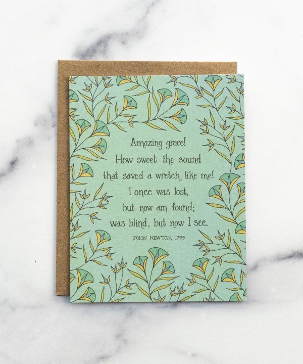 The Amazing Grace hymn greeting card, framed by dark mint and vintage yellow floral against a baby green background, shown with kraft paper envelope against a marble background.