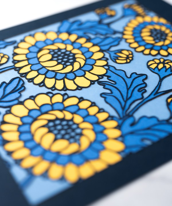 Detail image of the Layered Floral Papercut “Lou” (Cornflower), which is made using cardstock in hues of flag blue, Prussian blue, light gold, cornflower.