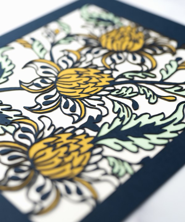 Detail image of the Layered Floral Papercut “Lyra” (Spearmint) which is made using cardstock in hues of flag blue, mustard, spearmint, tile green.
