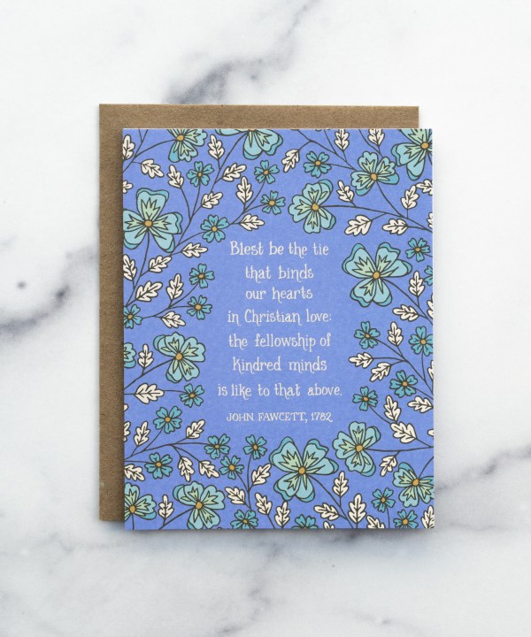 The Blest Be the Tie That Binds hymn greeting card, framed by sea mist and sea foam floral against a blue violet background, shown with a recycled kraft paper envelope against a marble background.