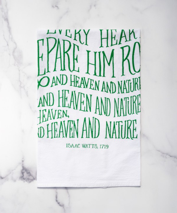 The new "Joy to the World" hymn tea towel features printed, hand-lettered text in winter ivy on a 100% cotton tea towel. Made in the USA. Shown here folded against a marble background.